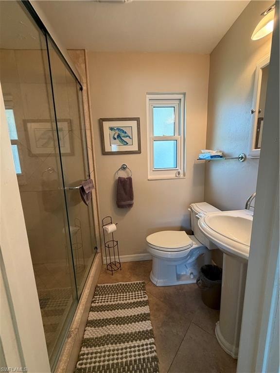 Pedestal sink with chrome fixtures, glass-enclosed shower, and built-in window providing natural light