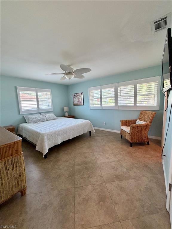 Spacious interior featuring large format floor tiles, multiple windows with white plantation shutters, and a ceiling fan with integrated lighting
