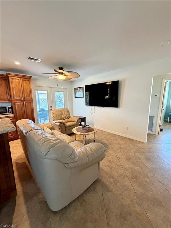 Open-concept living space featuring neutral tile flooring, a ceiling fan with integrated lighting, and white walls