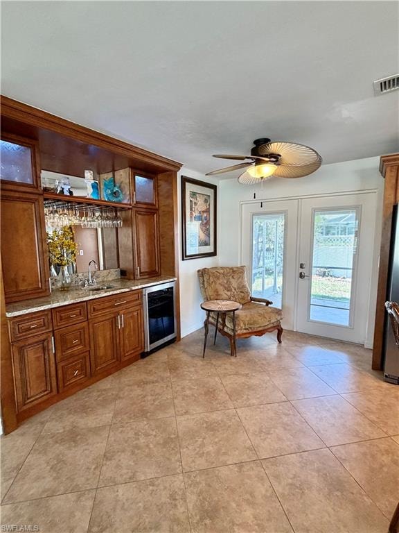 Built-in wet bar with wood cabinetry, undermount sink, and beverage refrigerator