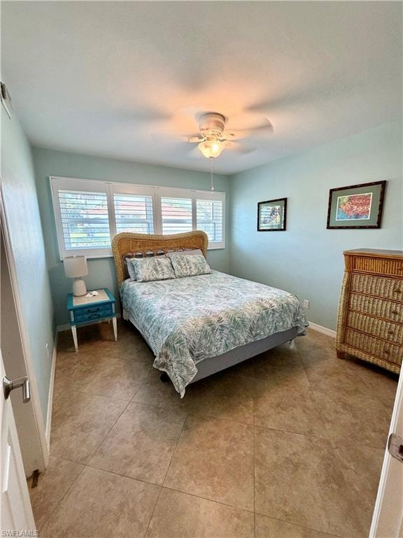 Bedroom featuring tiled flooring, a ceiling fan with integrated lighting, and multiple windows with plantation shutters