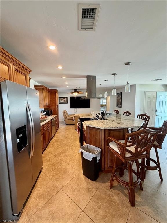 Spacious kitchen featuring wood cabinetry, stainless steel refrigerator, and a central island with a granite countertop