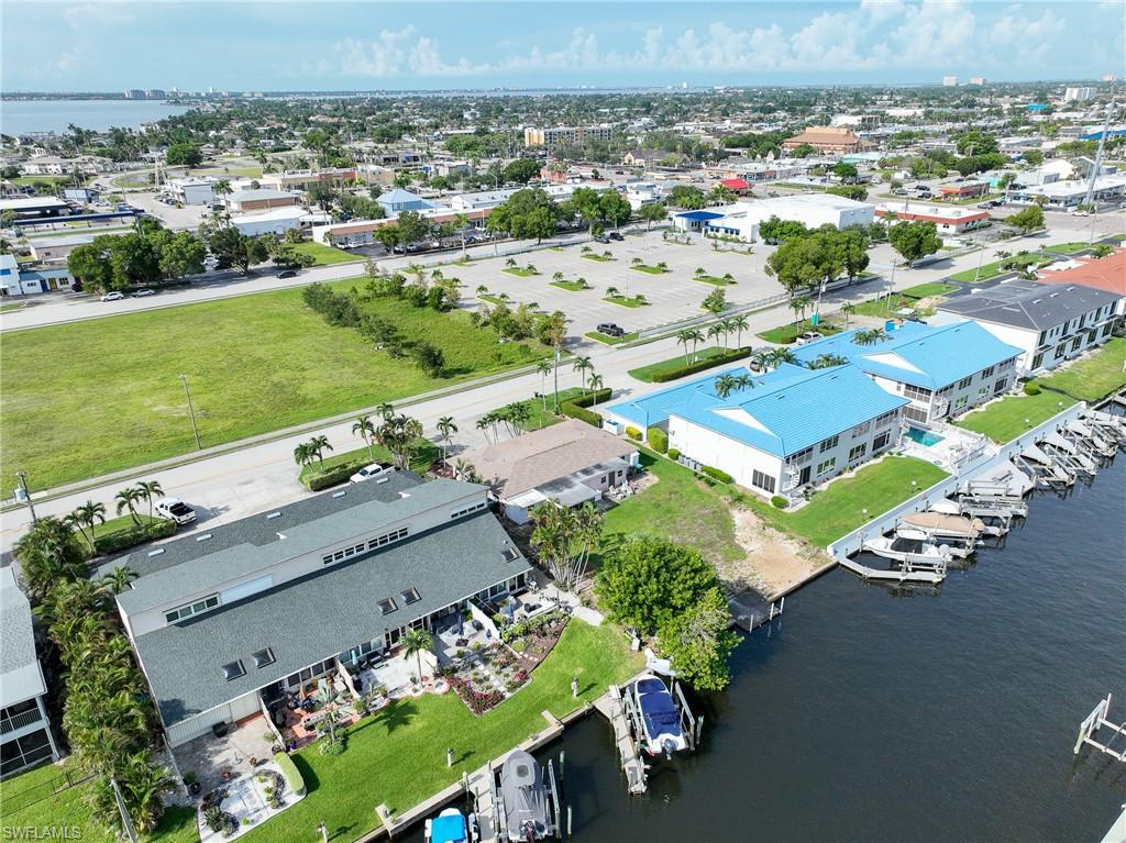 Waterfront property featuring multiple boat docks, a manicured lawn, and mature landscaping