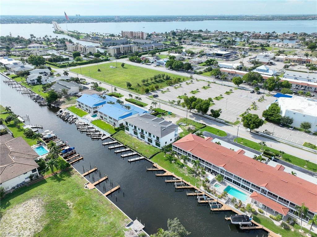 Waterfront property featuring a modern recreational facility with resort-style pool, expansive manicured lawn, covered boat slips with direct water access, and mature landscaping