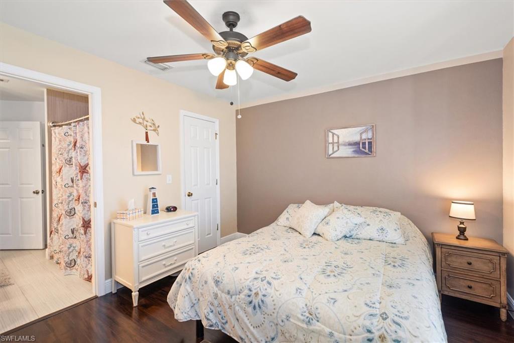 Bedroom featuring a ceiling fan with integrated lighting, wood-finish flooring, and a two-tone wall treatment