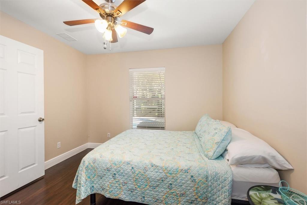 Room featuring wood-finish flooring, a ceiling fan with integrated lighting, and a single window with horizontal blinds