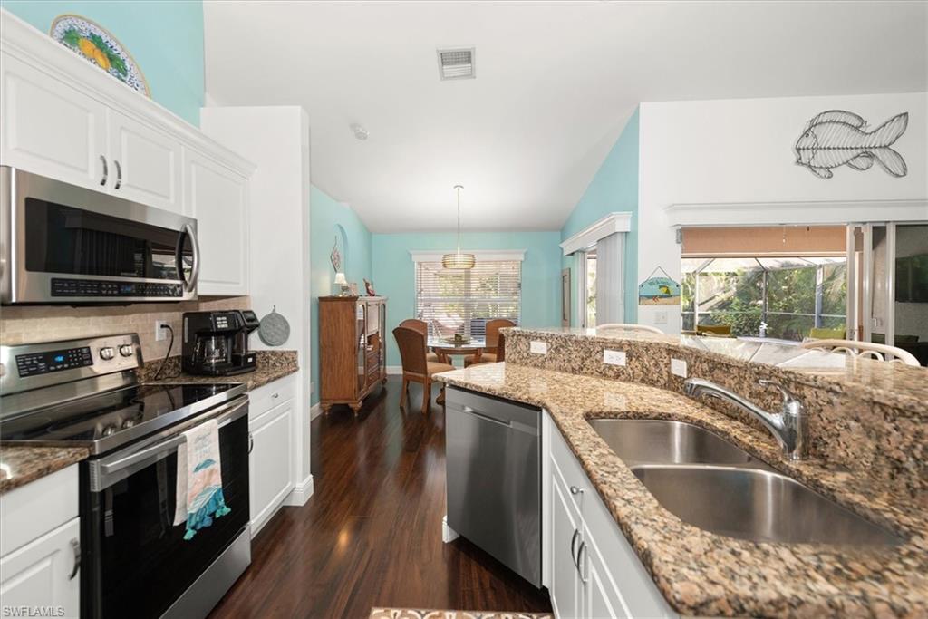 Kitchen featuring white cabinetry, stainless steel appliances, a double basin sink, and granite countertops