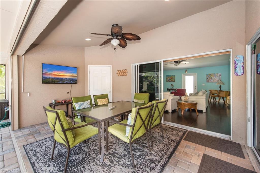 Screened lanai featuring paver flooring, a built-in ceiling fan, and sliding glass doors opening to interior living spaces