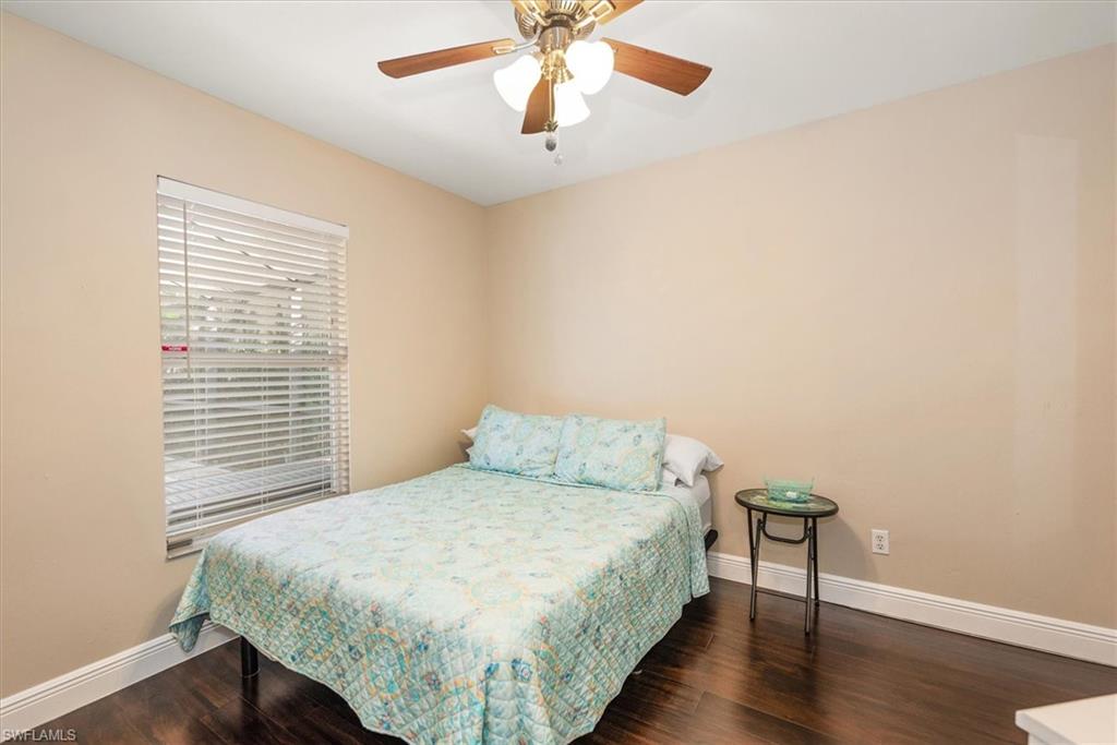 Bedroom featuring wood-finish flooring, a window with horizontal blinds, and a ceiling fan with integrated lighting