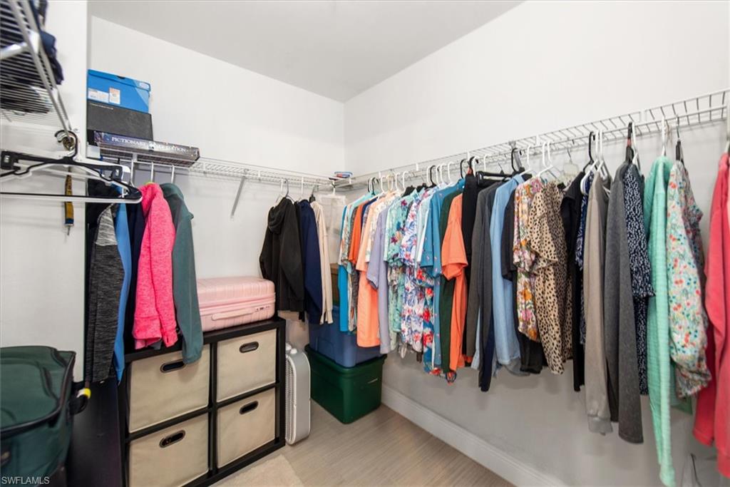 Walk-in closet featuring wire shelving, multiple hanging rods, and light-tone wood-finish flooring