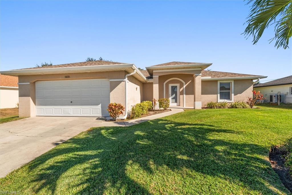 Single-story stucco residence featuring a two-car garage, arched entry, and a concrete driveway