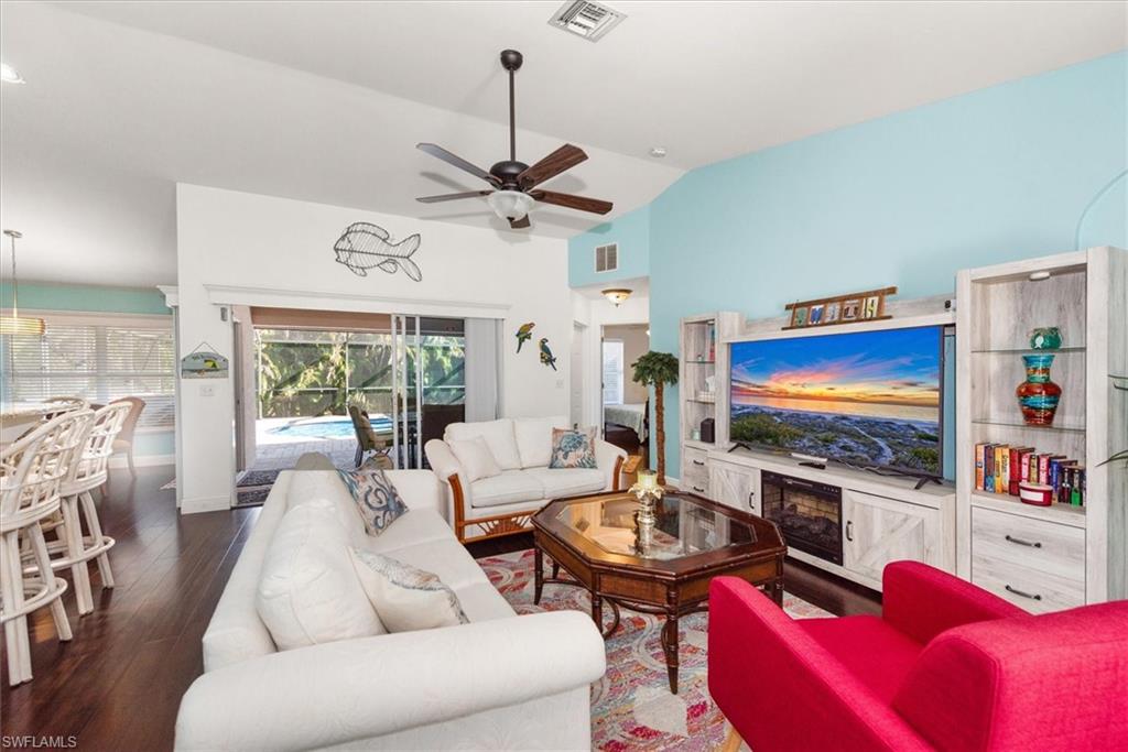 Living area featuring vaulted ceilings, dark wood-finish flooring, and direct access to a screened outdoor space