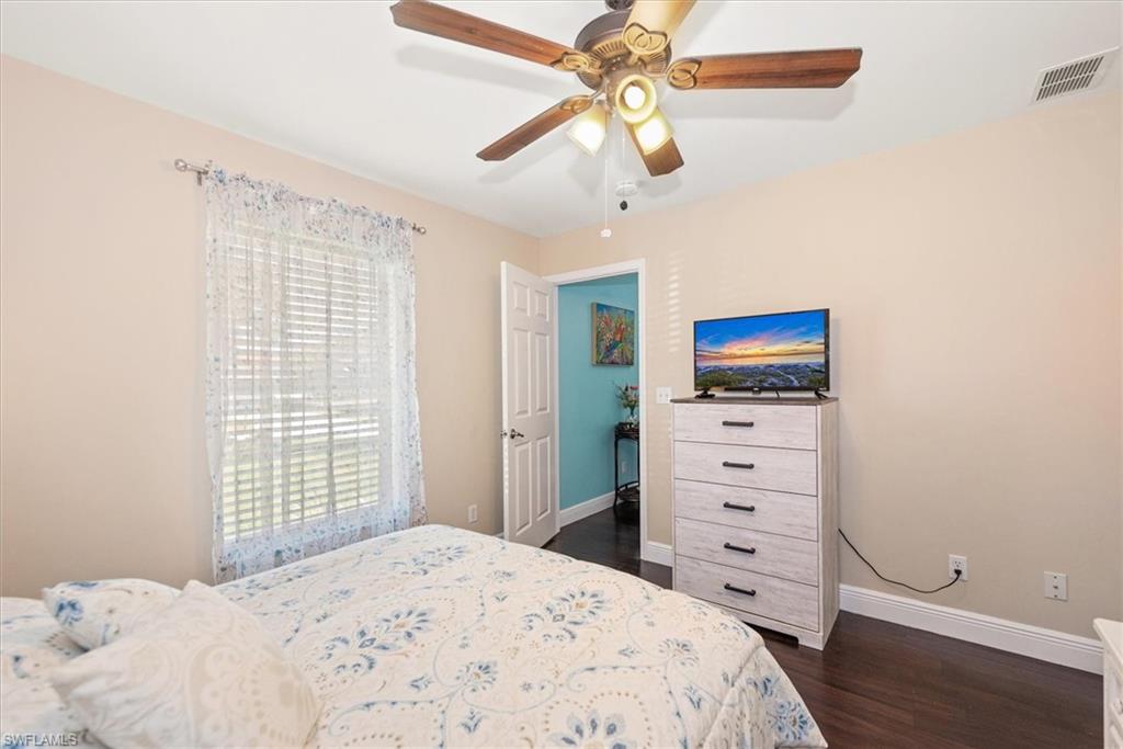 Bedroom featuring wood-finish flooring, a ceiling fan with integrated lighting, and a window with horizontal blinds