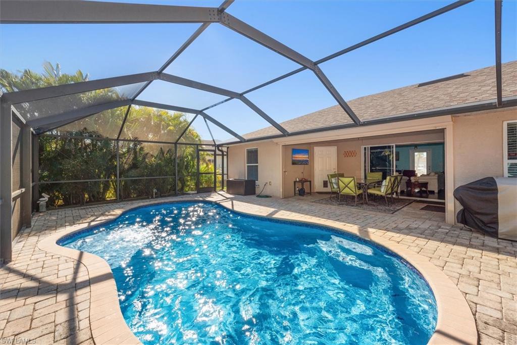 Screened lanai featuring a freeform swimming pool, paver deck, and covered patio area with direct access to the interior