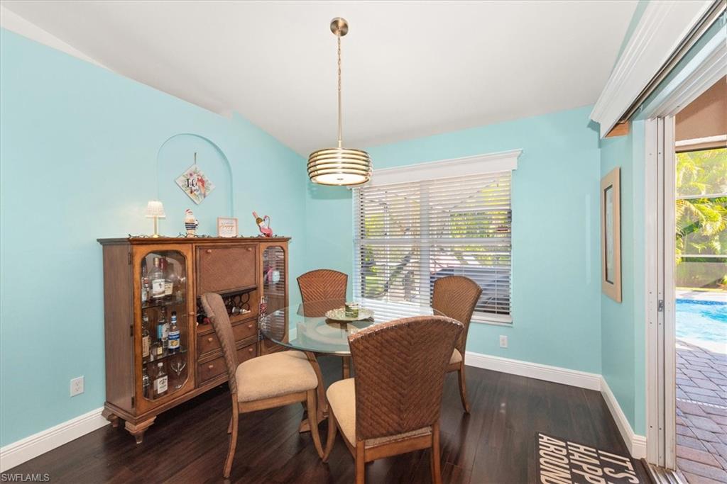 Dining area featuring dark wood-finish flooring, a contemporary pendant light fixture, and a window with blinds