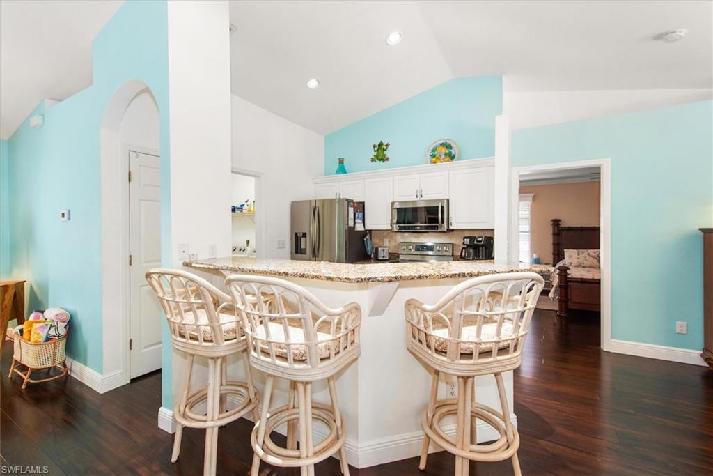 Kitchen featuring a breakfast bar with stone-finish countertop, white cabinetry, and stainless steel appliances
