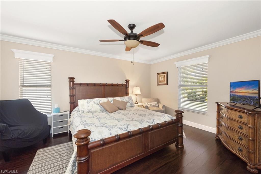 Spacious room featuring dark wood-finish flooring, light-colored walls, and a ceiling fan with integrated lighting