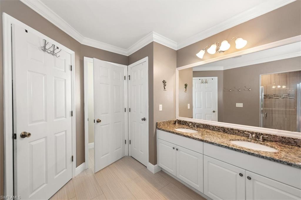 Bathroom featuring a dual vanity with a granite-style countertop, white cabinetry, and undermount sinks