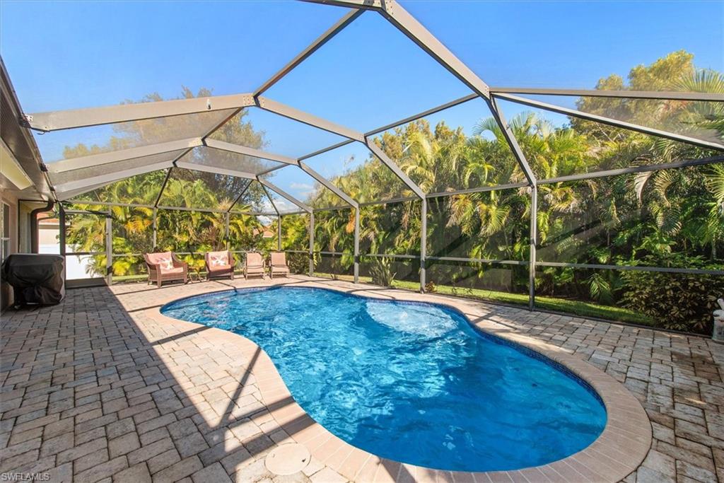 Screened pool enclosure featuring a kidney-shaped pool with a paver deck