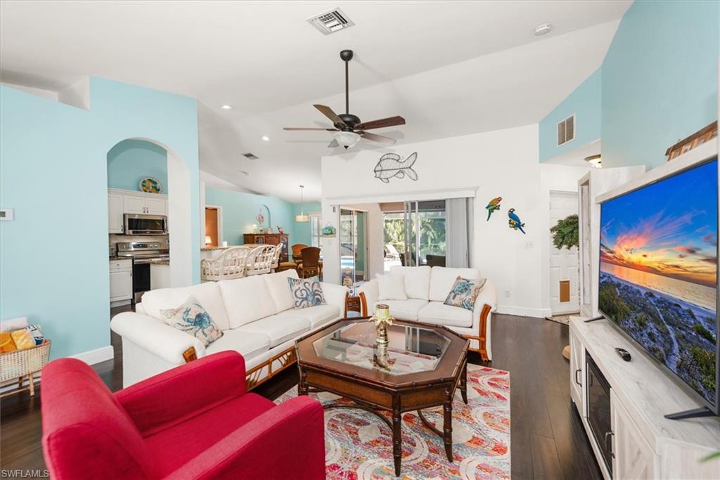 Spacious living area featuring wood-finish flooring, vaulted ceilings, and a ceiling fan