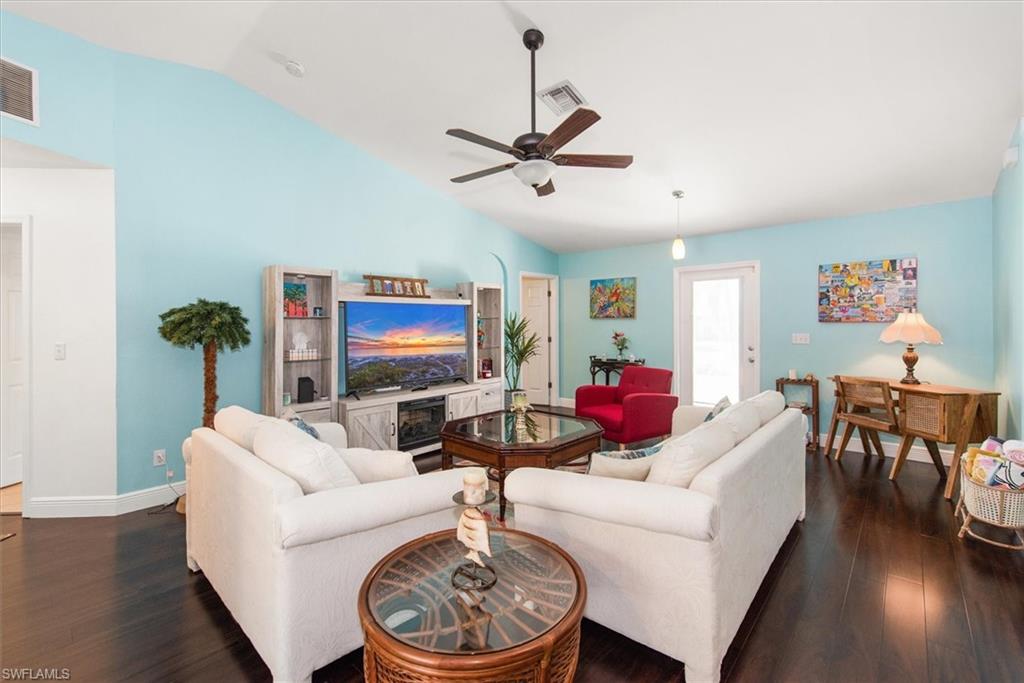 Open living space featuring dark wood-finish flooring, light blue painted walls, and a vaulted ceiling