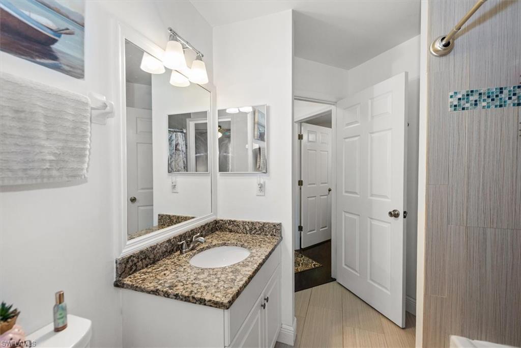 Bathroom featuring a white vanity with a speckled countertop, an undermount sink, and a large wall-mounted mirror