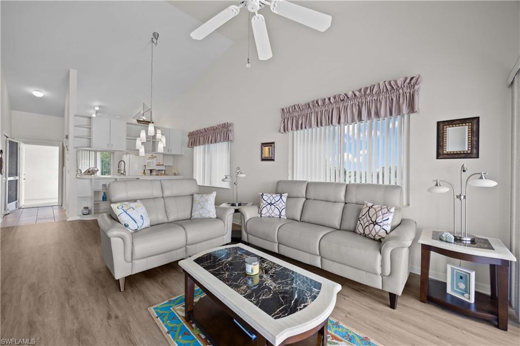 Living area with high vaulted ceiling, light wood-style floors, and ceiling fan