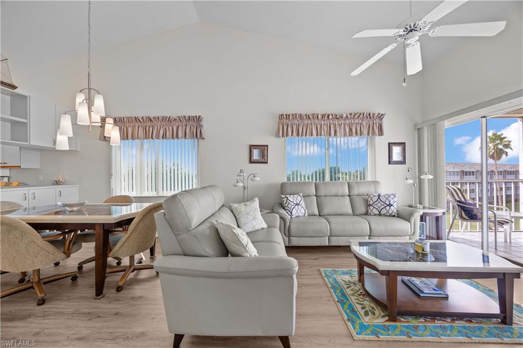Living room featuring high vaulted ceiling, plenty of natural light, wood finished floors, and ceiling fan