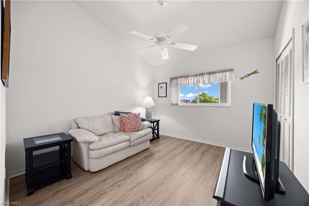 Living room with light wood-style floors, vaulted ceiling, and a ceiling fan