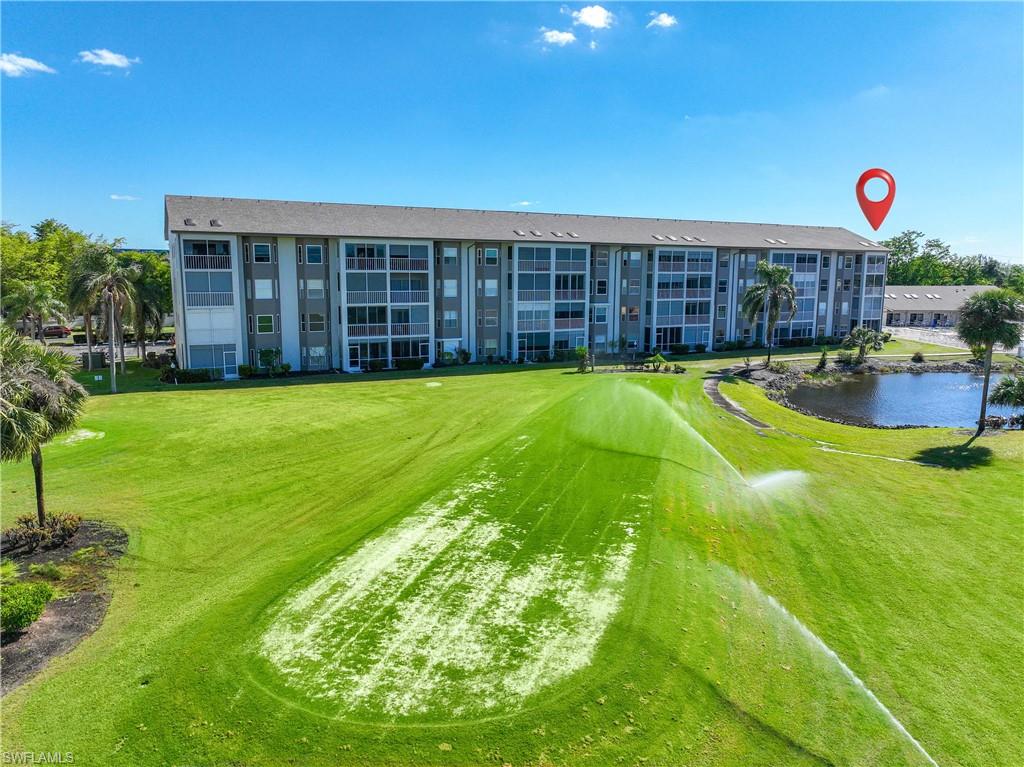 View of community with view of golf course, a water view, and a yard