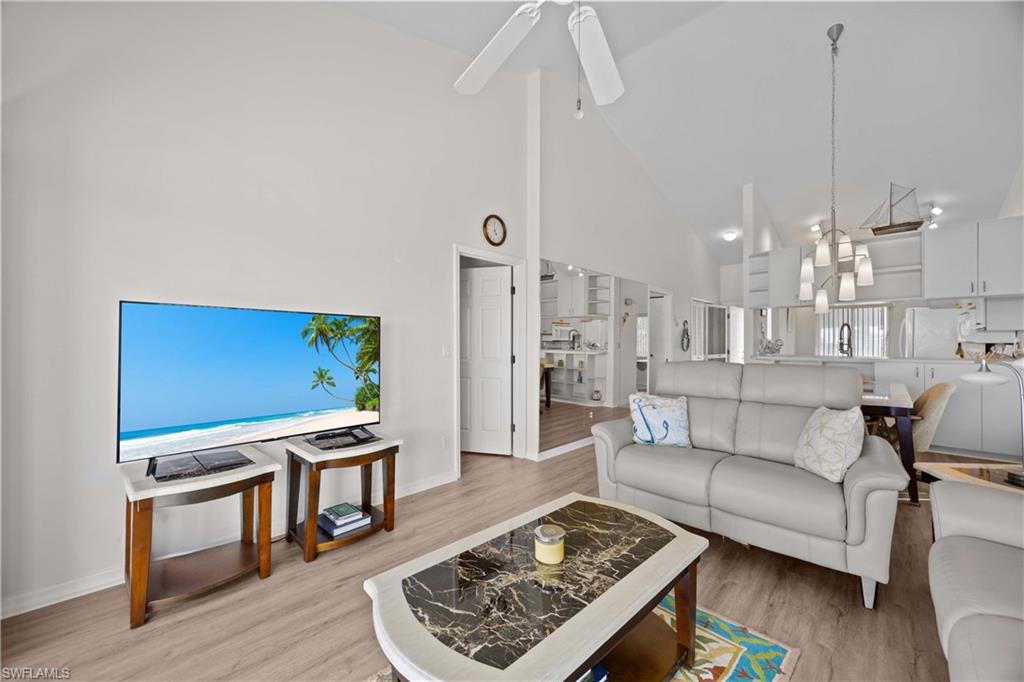 Living room with high vaulted ceiling, light wood finished floors, and a ceiling fan
