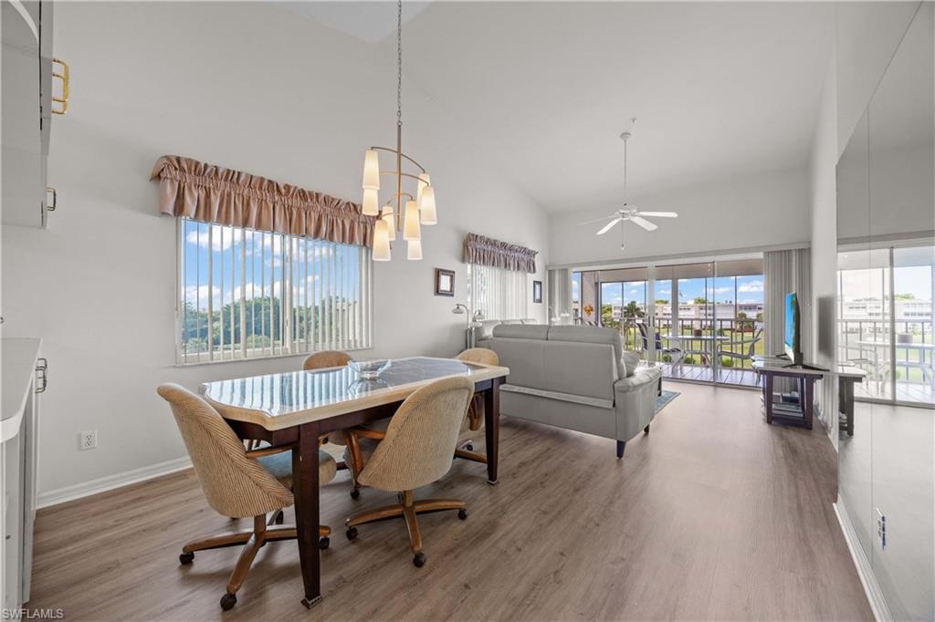 Dining area featuring high vaulted ceiling, ceiling fan, light wood-style flooring, and a chandelier