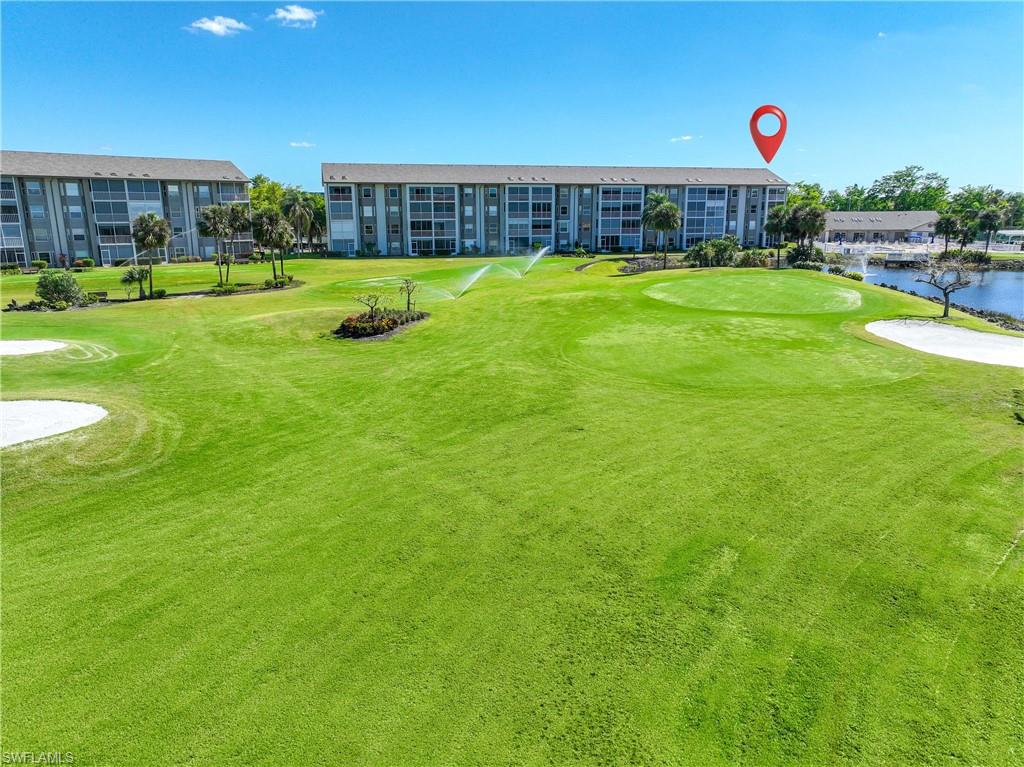View of community with golf course view, a water view, and a lawn