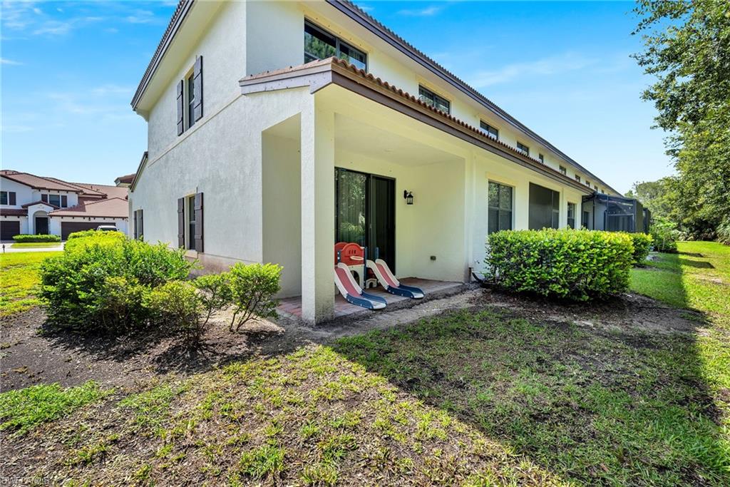 Stucco exterior with a covered patio, multiple windows, and a landscaped perimeter