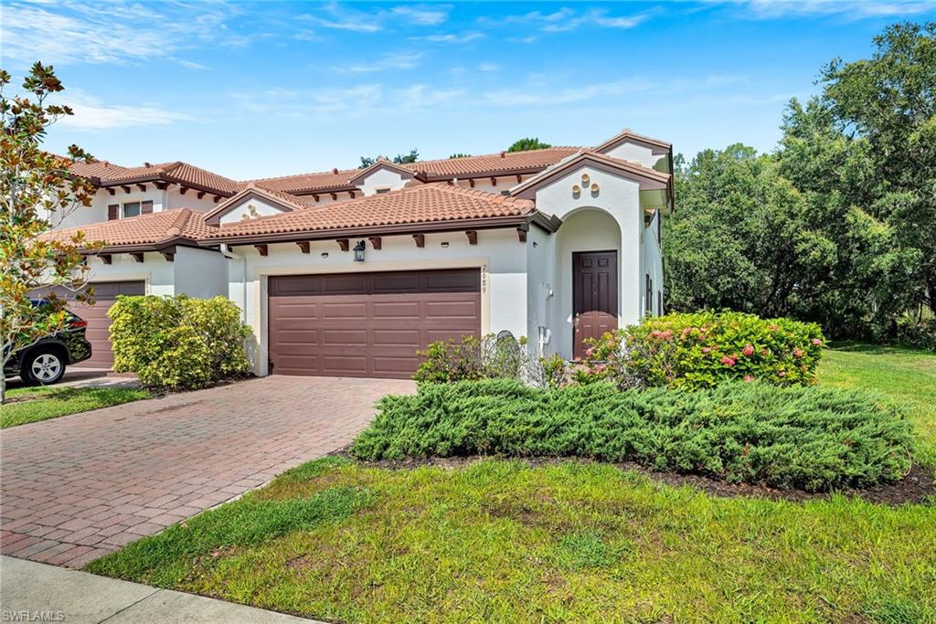 Contemporary Mediterranean-style residence featuring a terracotta tile roof, stucco exterior, an arched entryway, a paver driveway, and an attached garage