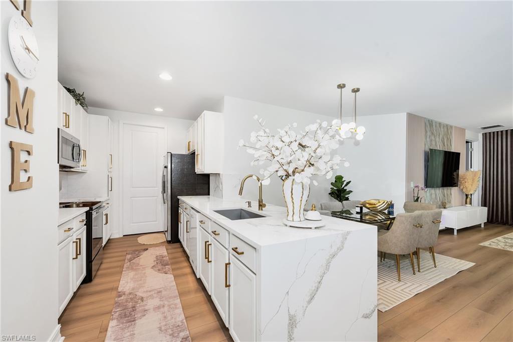 Galley kitchen featuring white cabinetry, stainless steel appliances, and wood-finish flooring