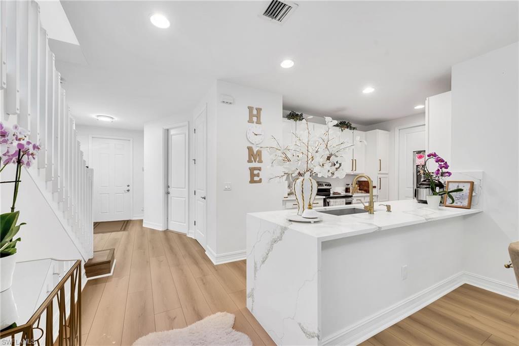 Open-concept kitchen with a waterfall island, white cabinetry, and gold-finish hardware