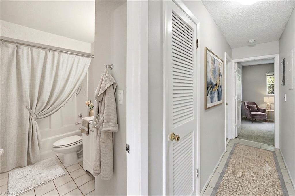 Virtually staged photo showing full bathroom and hallway to bedrooms.