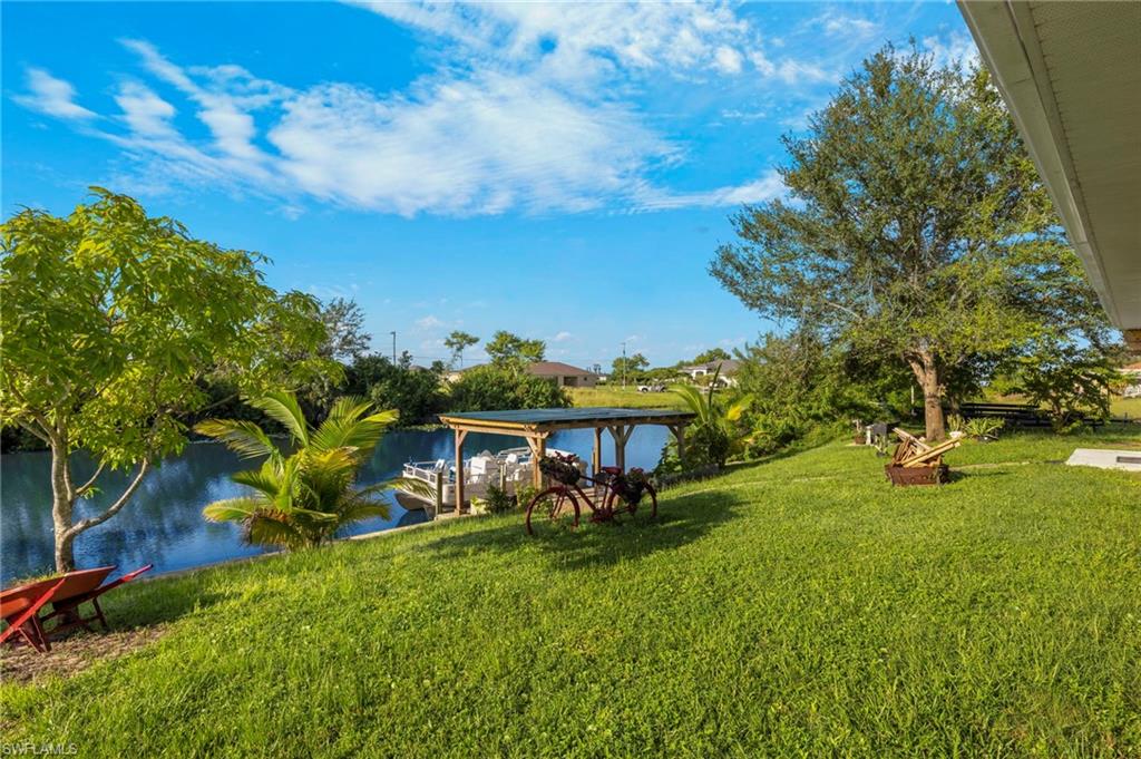Grassy yard with waterfront access, featuring a covered dock structure