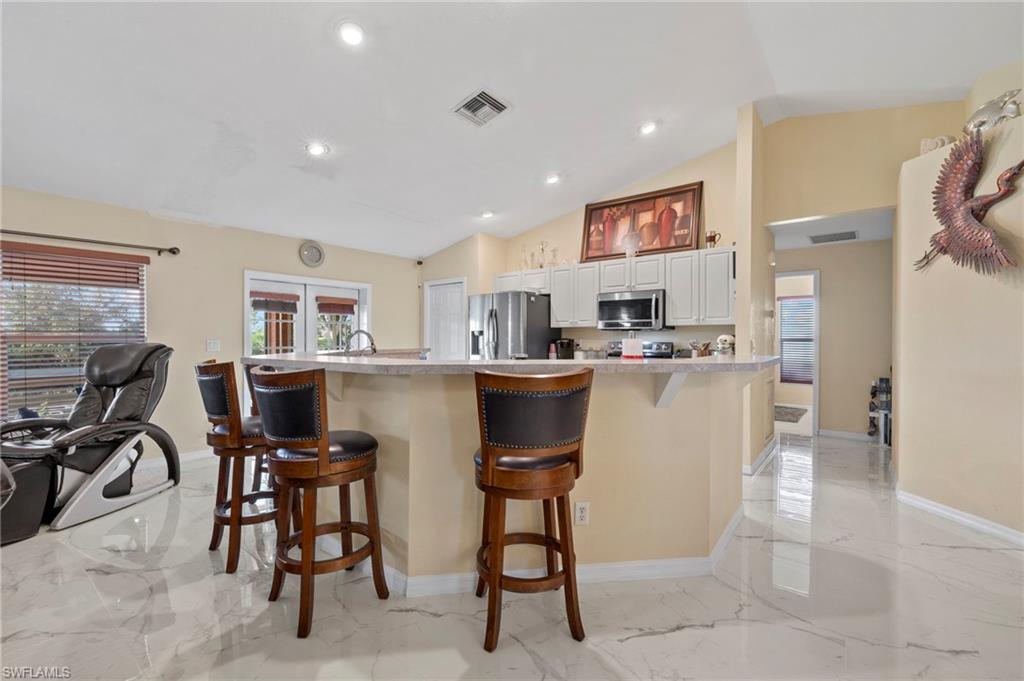 Kitchen with a breakfast bar featuring light countertops, white cabinetry, and stainless steel appliances