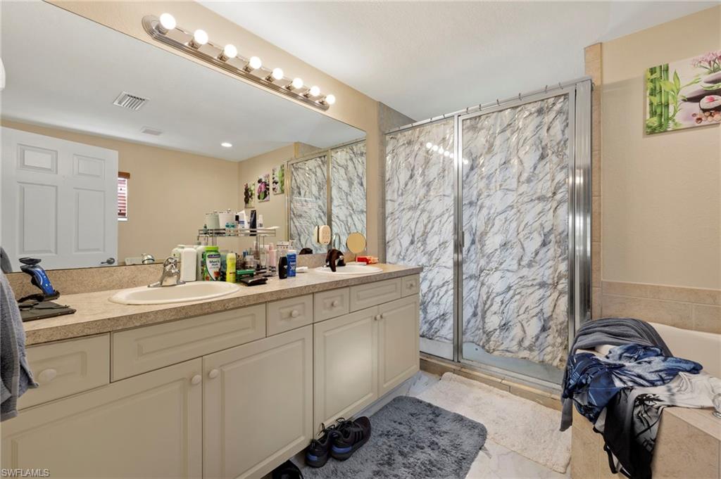 Bathroom featuring a double vanity with integrated sinks and a light-toned countertop, a full-width wall mirror, and a linear vanity light fixture with multiple bulbs