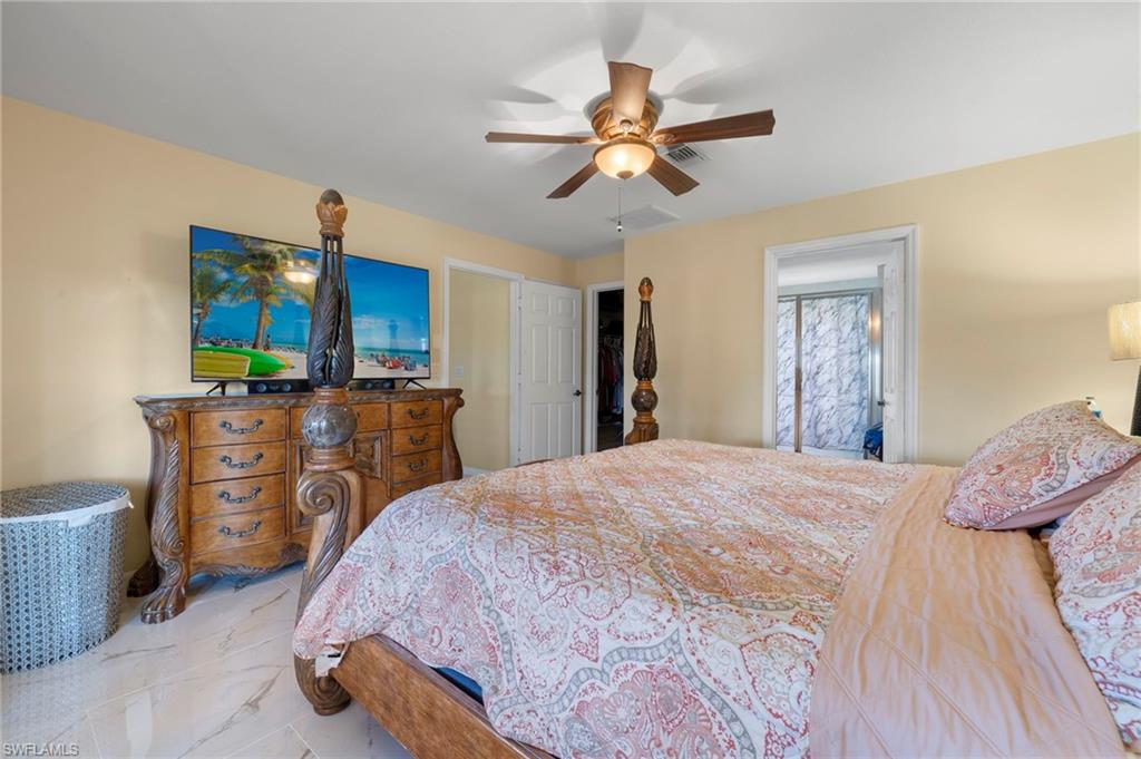 Room featuring light-toned walls, a ceiling fan with integrated lighting, and a doorway revealing a bathroom