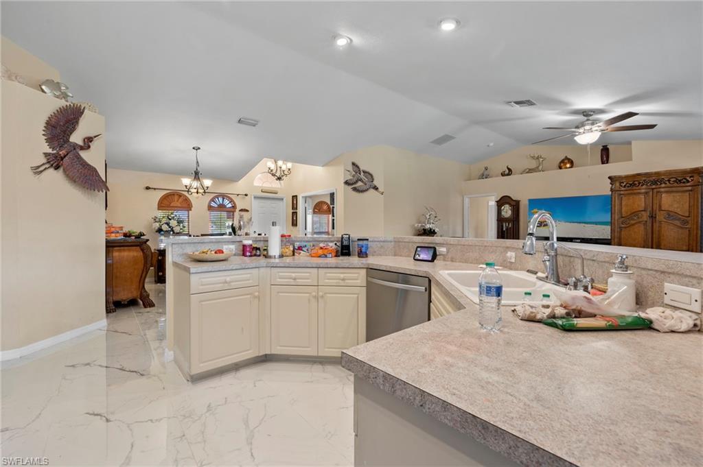 Kitchen featuring cream-toned cabinetry, light-toned countertops, and a double basin sink with a high-arc faucet