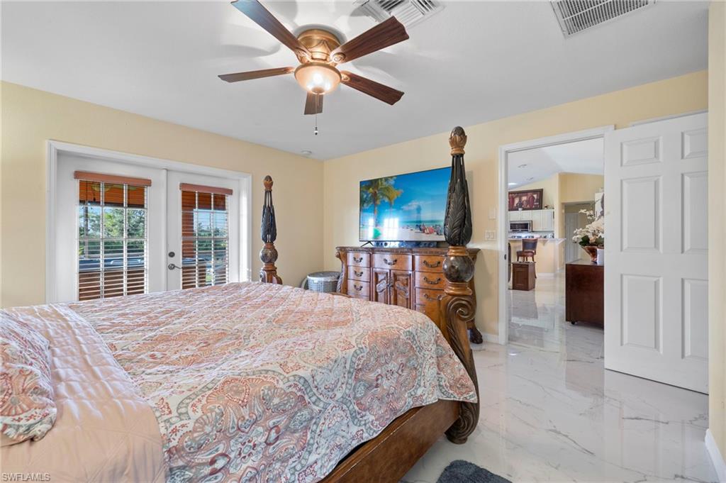 Spacious room featuring white large-format tile flooring, a ceiling fan with integrated lighting, and direct outdoor access through French doors with internal blinds