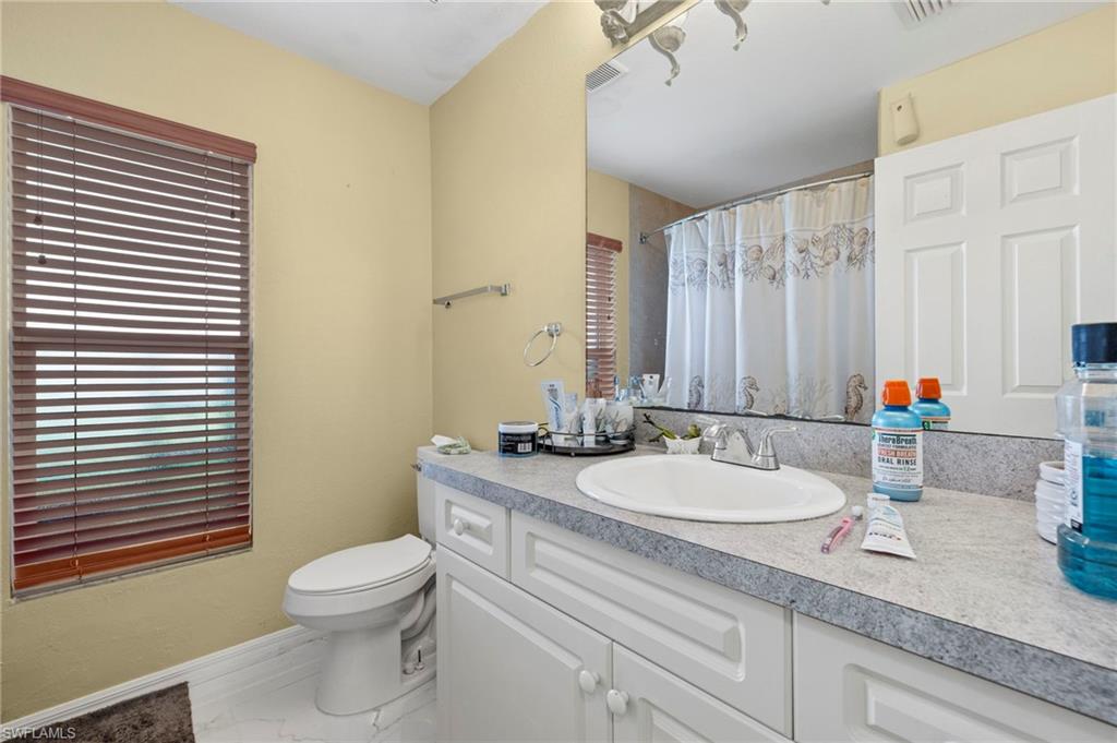 Bathroom featuring a vanity with a laminate countertop, integrated sink, and white cabinetry with beadboard detailing