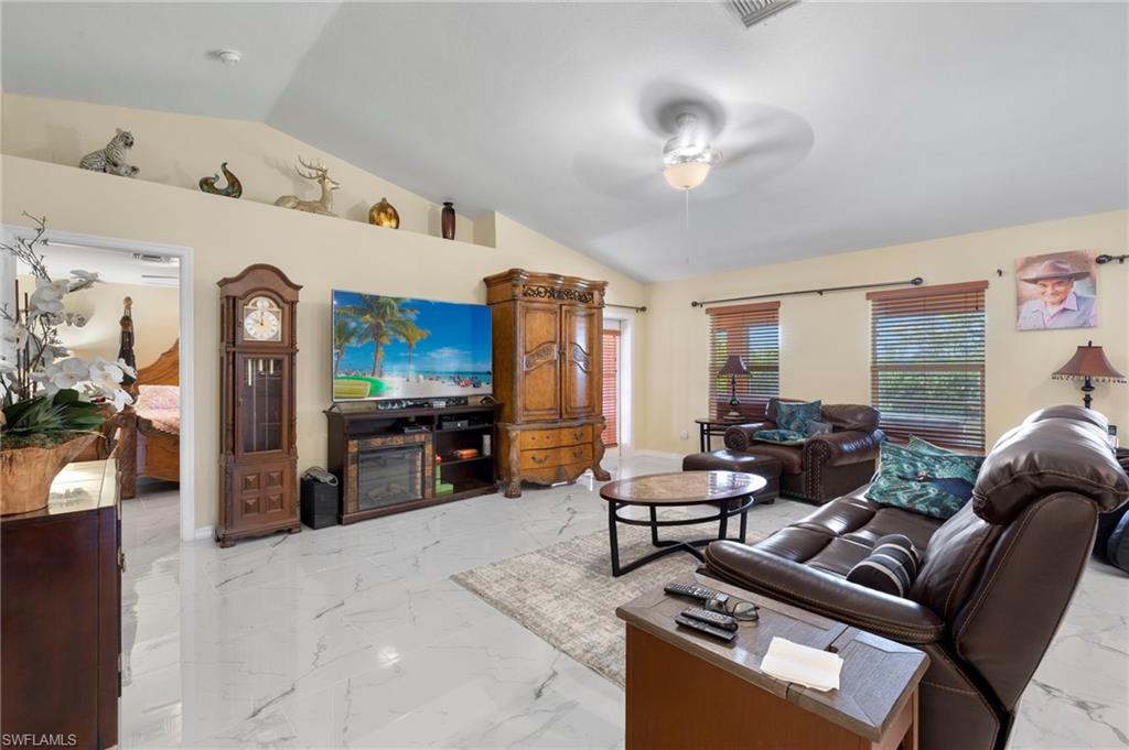 Spacious living area featuring vaulted ceilings, light-toned walls, and large format Porcelan tile flooring