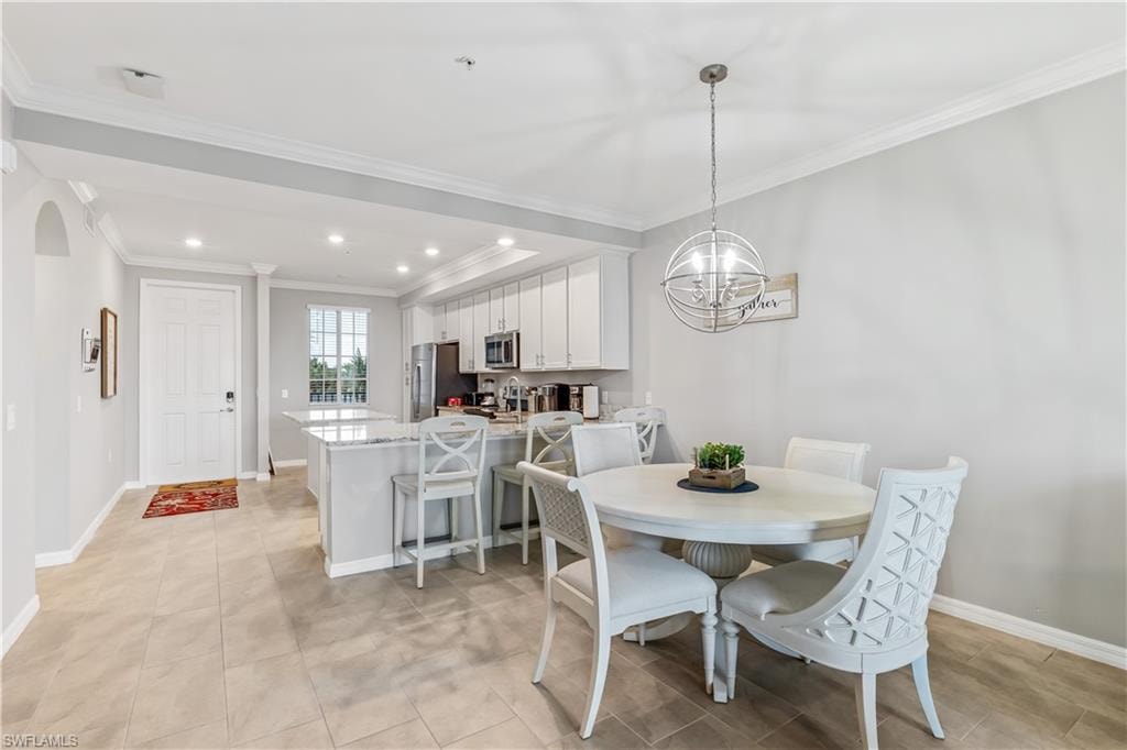 Dining area featuring a chandelier, light tile floors, and crown molding