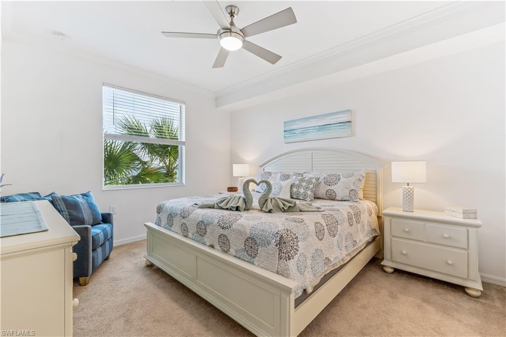 Bedroom with light carpet, ornamental molding, and ceiling fan