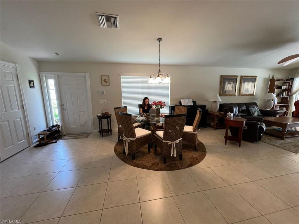 Dining room with light tile patterned flooring and ceiling fan with notable chandelier