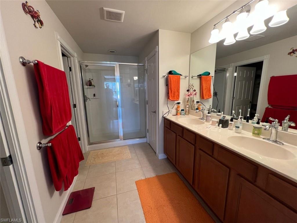 Bathroom featuring a shower with door, tile patterned floors, and double sink vanity
